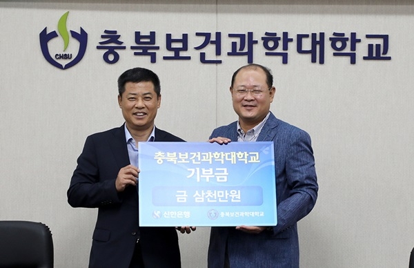 정도영 신한은행 충북본부장(왼쪽)이 박용석 총장에게 발전기금을 전달하고 있다. /충북보과대 제공