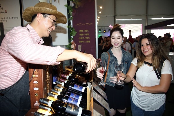 김덕현 컨츄리농원 대표(왼쪽)가 대한민국 와인축제장을 찾은 외국인들에게 자신이 빚은 와인을 따라주고 있다.