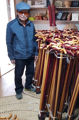 서재원 할아버지가 보은군에 전달하기 위해 손수 만든 지팡이 1000개 옆에서 사진을 찍고 있다.
