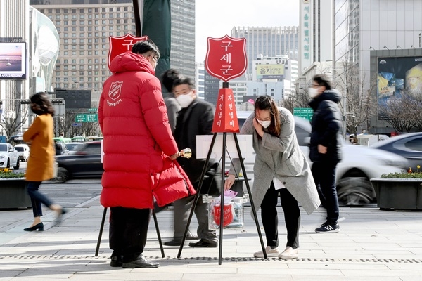 서울 종로구 광화문광장에 설치된 구세군 자선냄비에 한 시민이 마스크를 기부하고 있다.